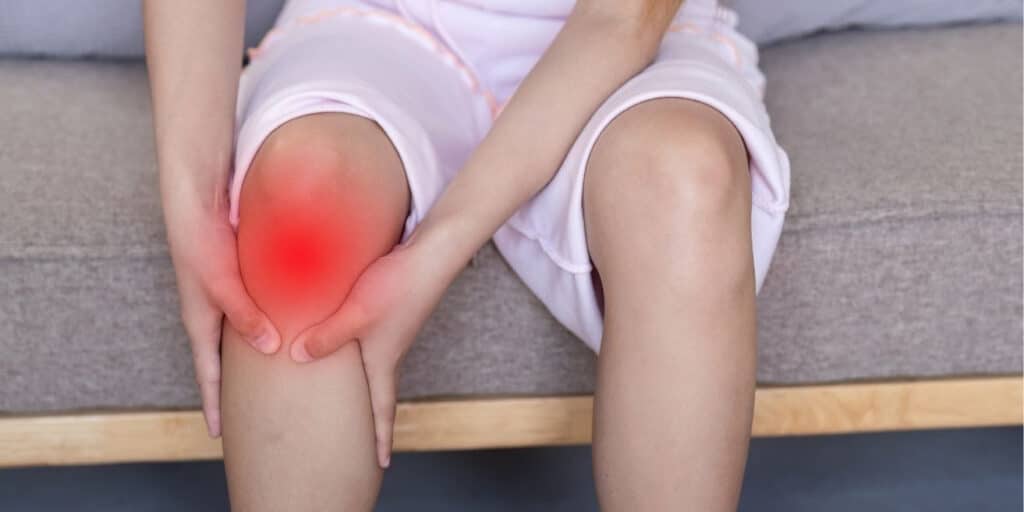 Woman holding her knee with pain highlighted in red