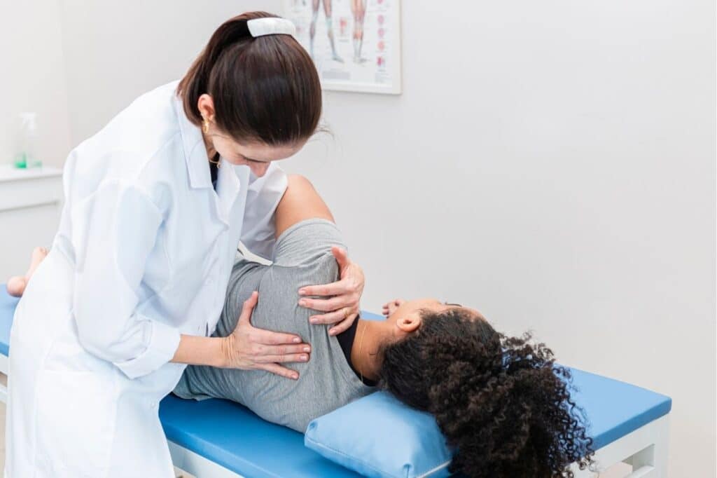 Physiotherapist assessing a patient's shoulder on a treatment couch